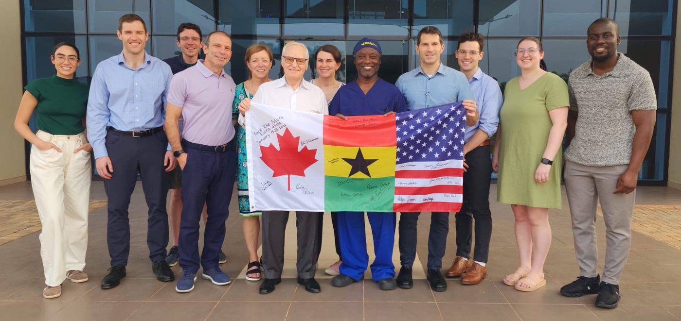 The Face the Future mission team in Accra, Ghana, holding a signed flag combining the Canadian, Ghanaian, and American flags