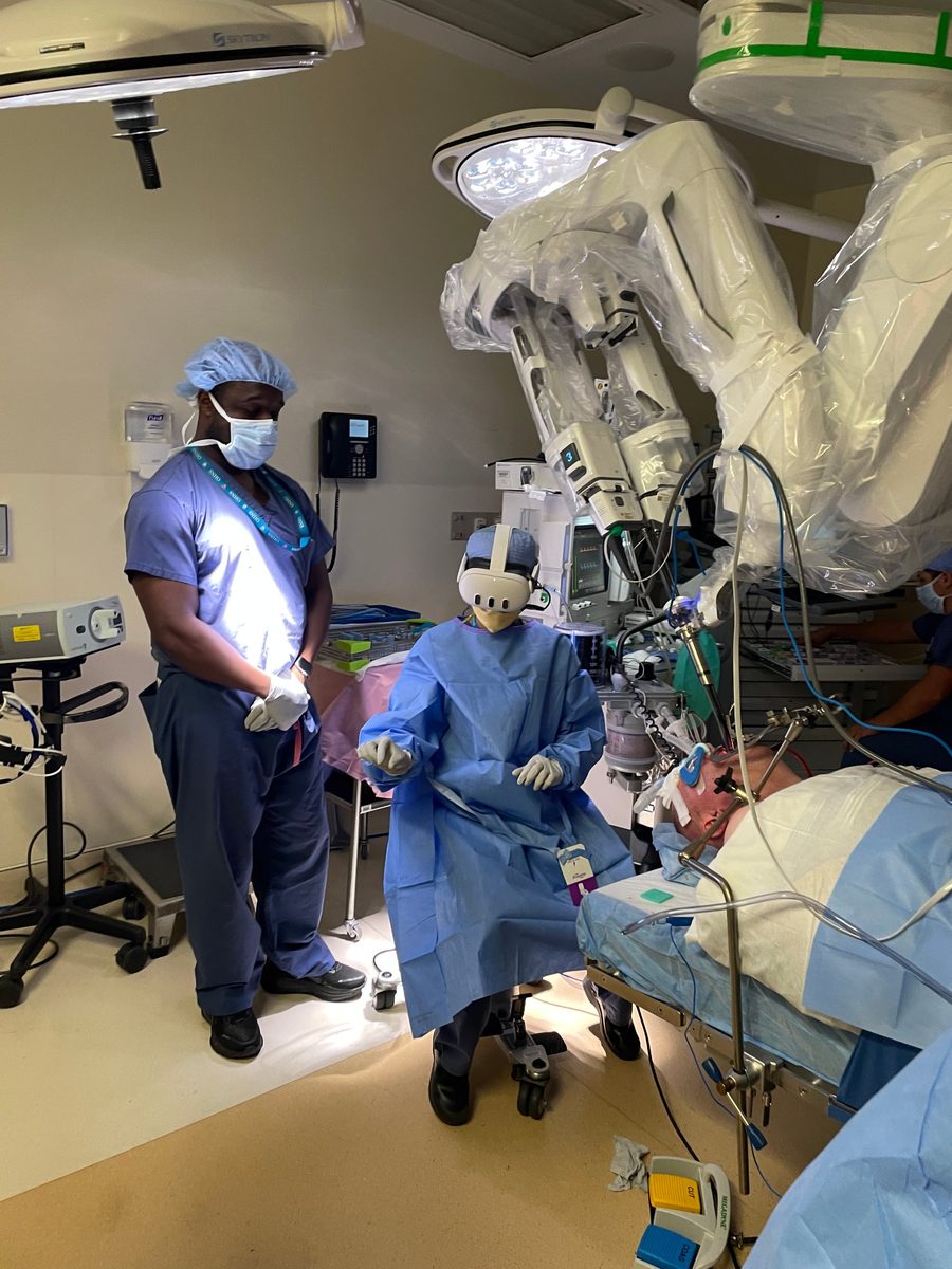 A team member wearing a mixed-reality headset beside the surgical robot during an operation